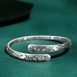 Bracelet lotus en argent tibétain avec motif de fleurs ciselées en relief et inscription en sanskrit