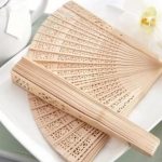 Éventail japonais traditionnel en bois de santal aux découpes florales et géométriques ajourées
